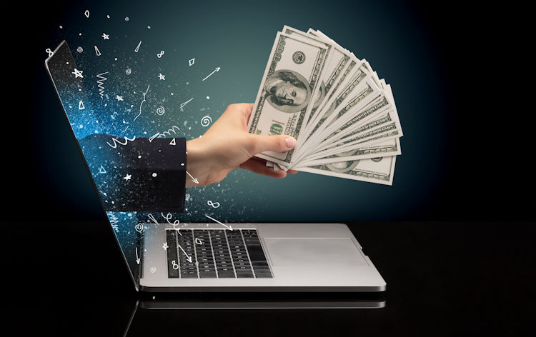 Hand with money going through computer.